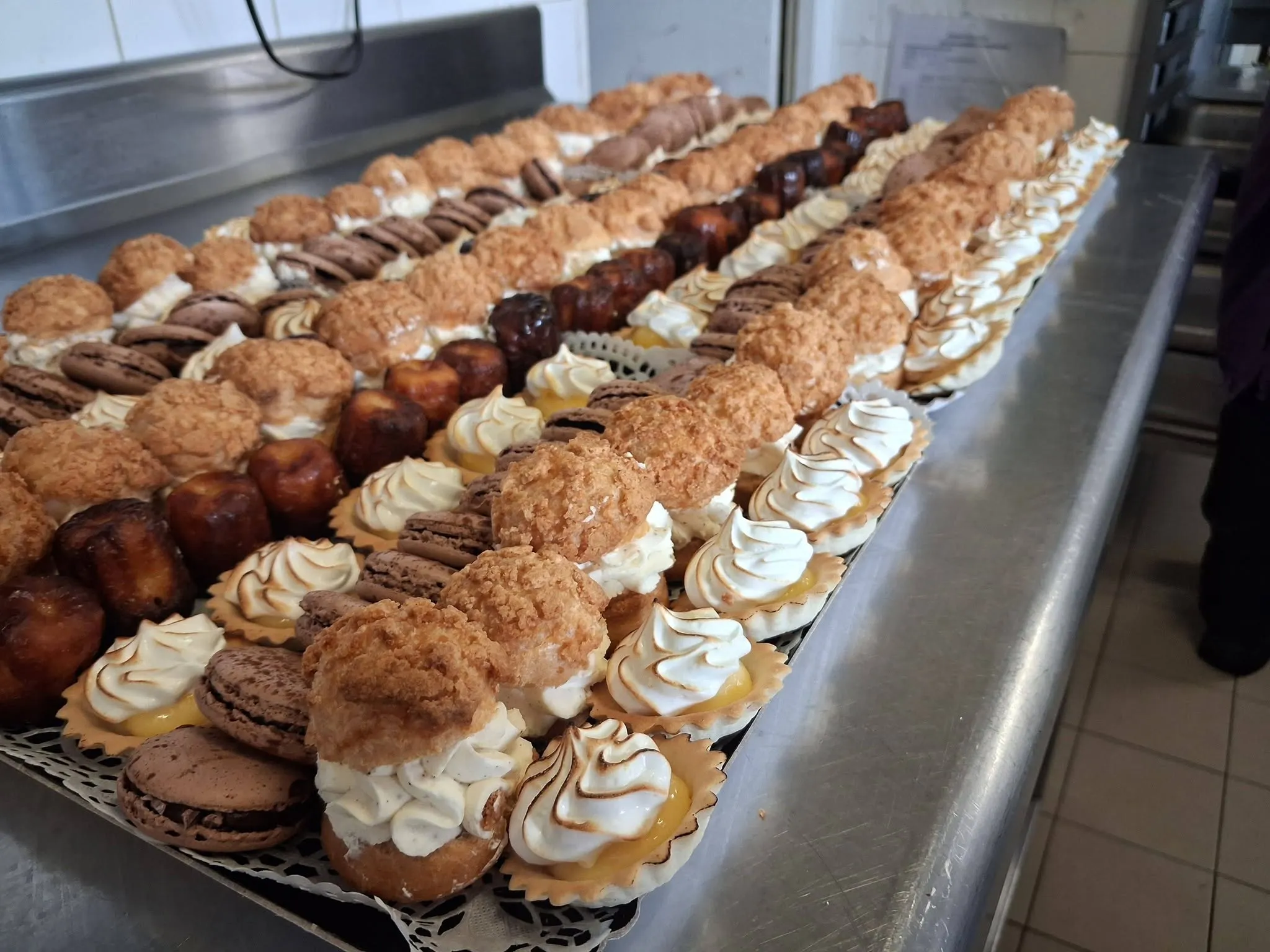 Grand plateau de pâtisseries variées sur un comptoir inox en cuisine