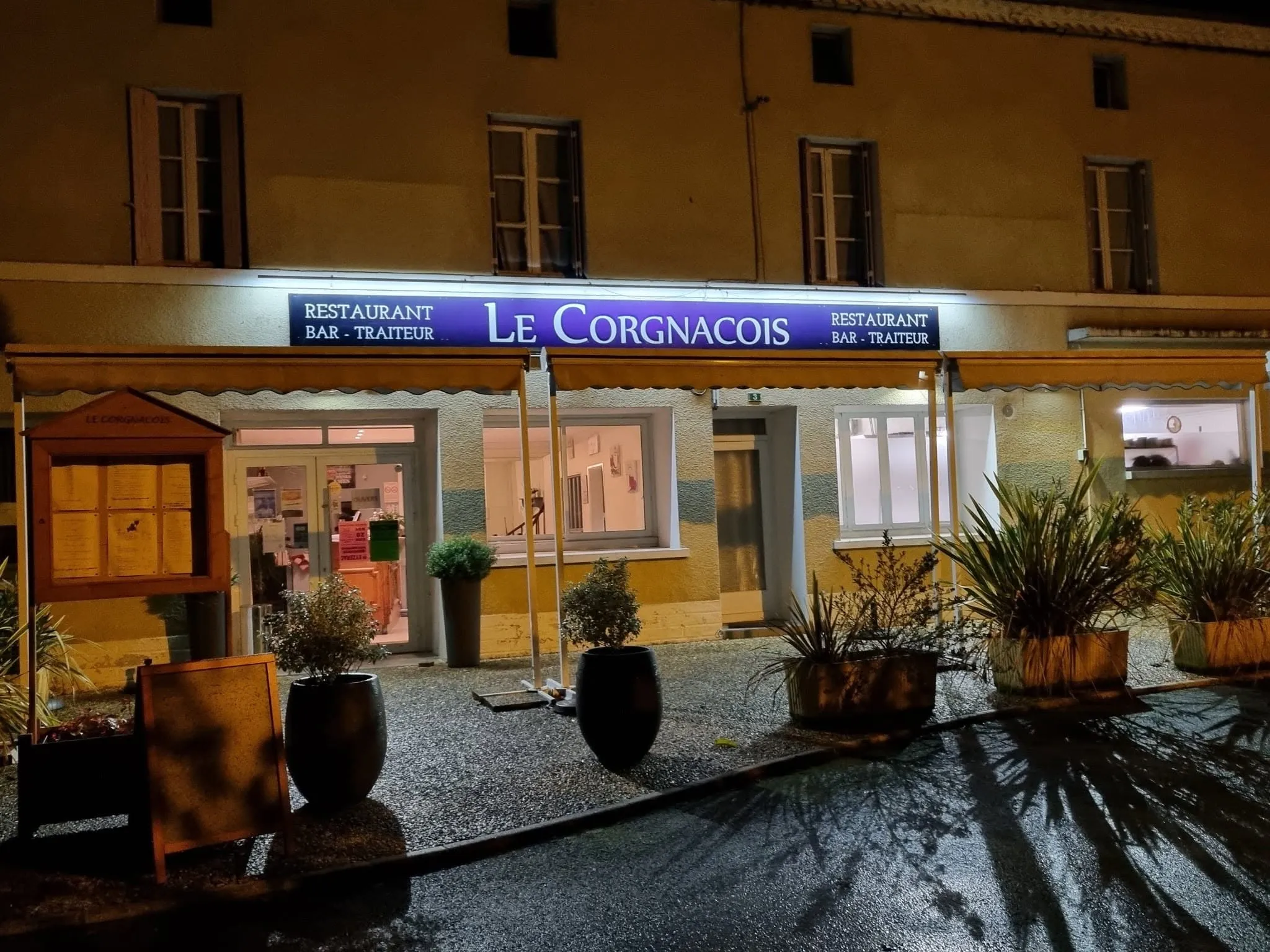 Façade éclairée du restaurant Le Corgnacois avec son enseigne restaurant, bar et traiteur