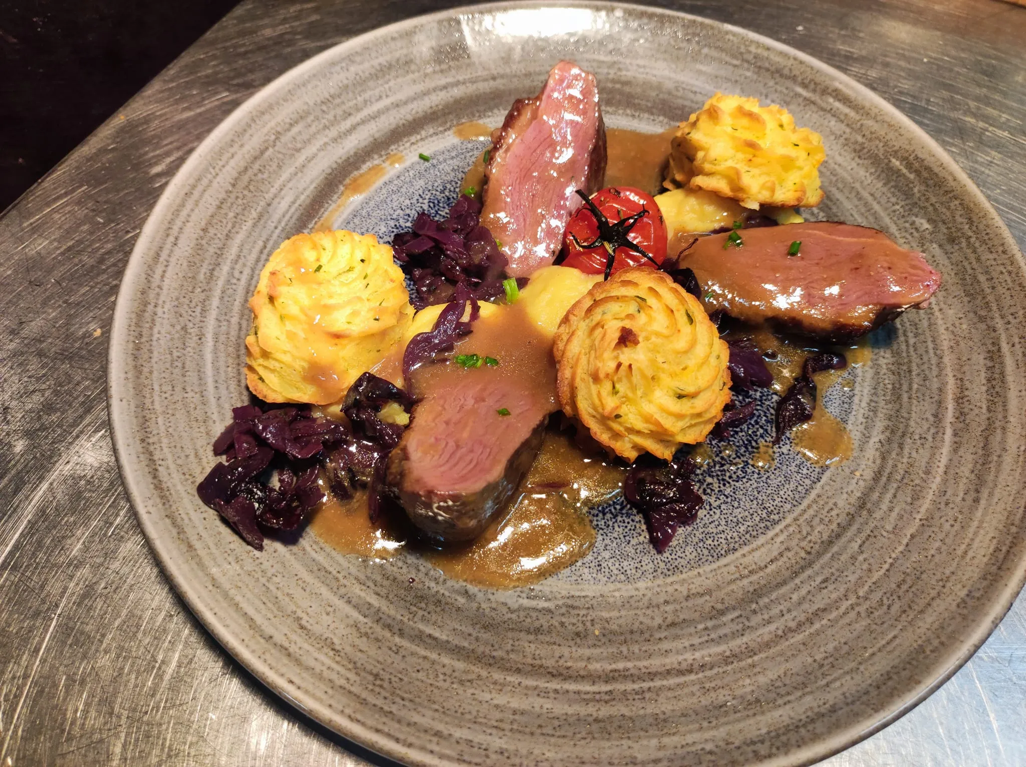 Assiette de magret de canard avec pommes duchesse, chou rouge et sauce