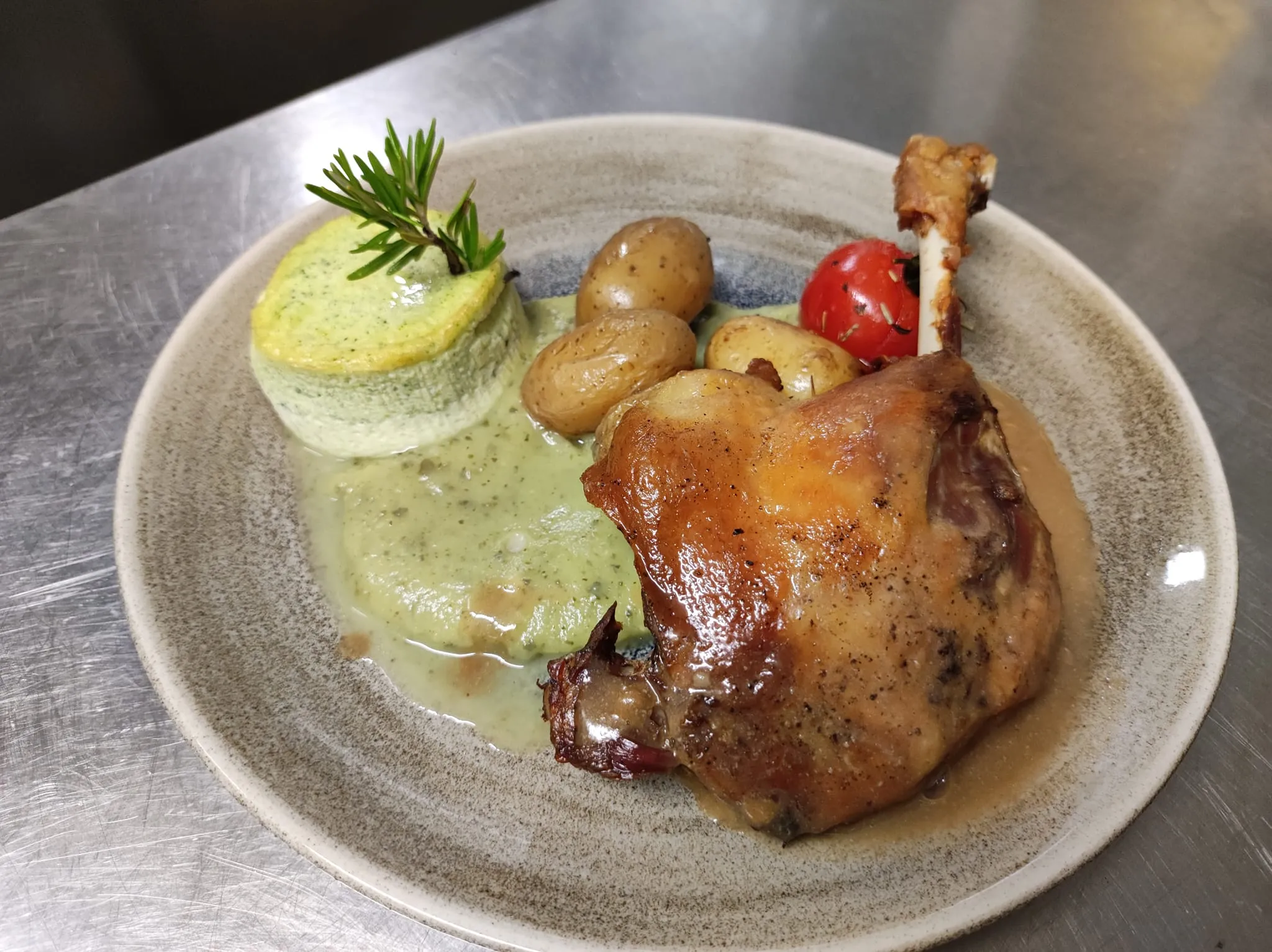 Assiette de poulet rôti avec pommes de terre et garniture verte, préparée dans un restaurant traditionnel