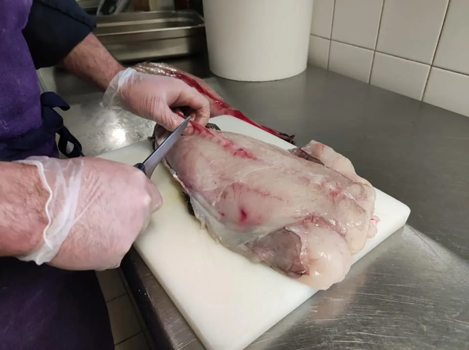 Chef préparant un poisson frais sur une planche en cuisine