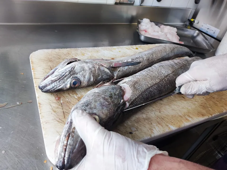Deux poissons frais préparés sur une planche dans une cuisine professionnelle