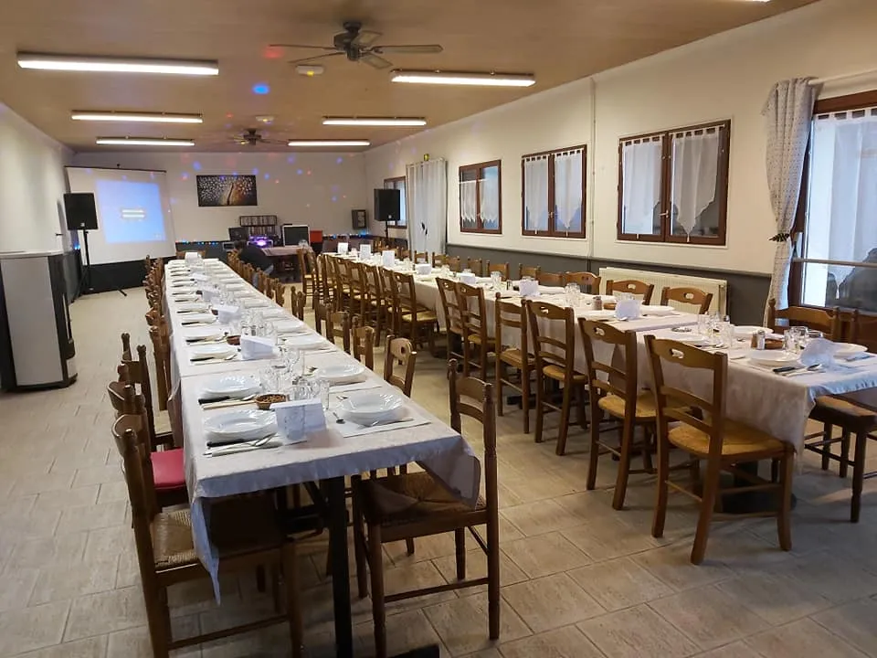 Salle du restaurant dressée pour un repas de groupe avec écran de projection