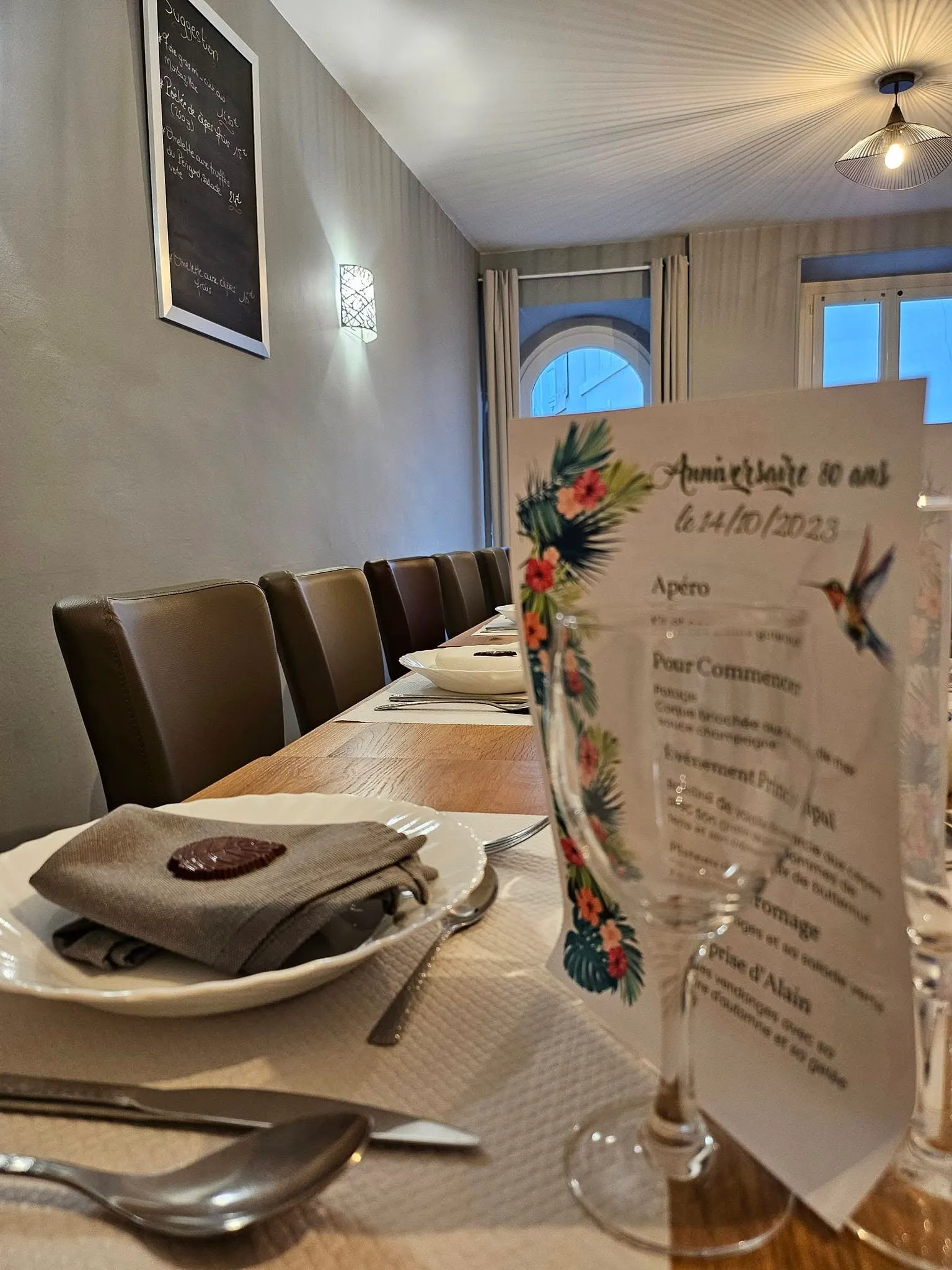 Table dressée avec assiettes, serviettes et menu d’anniversaire au premier plan