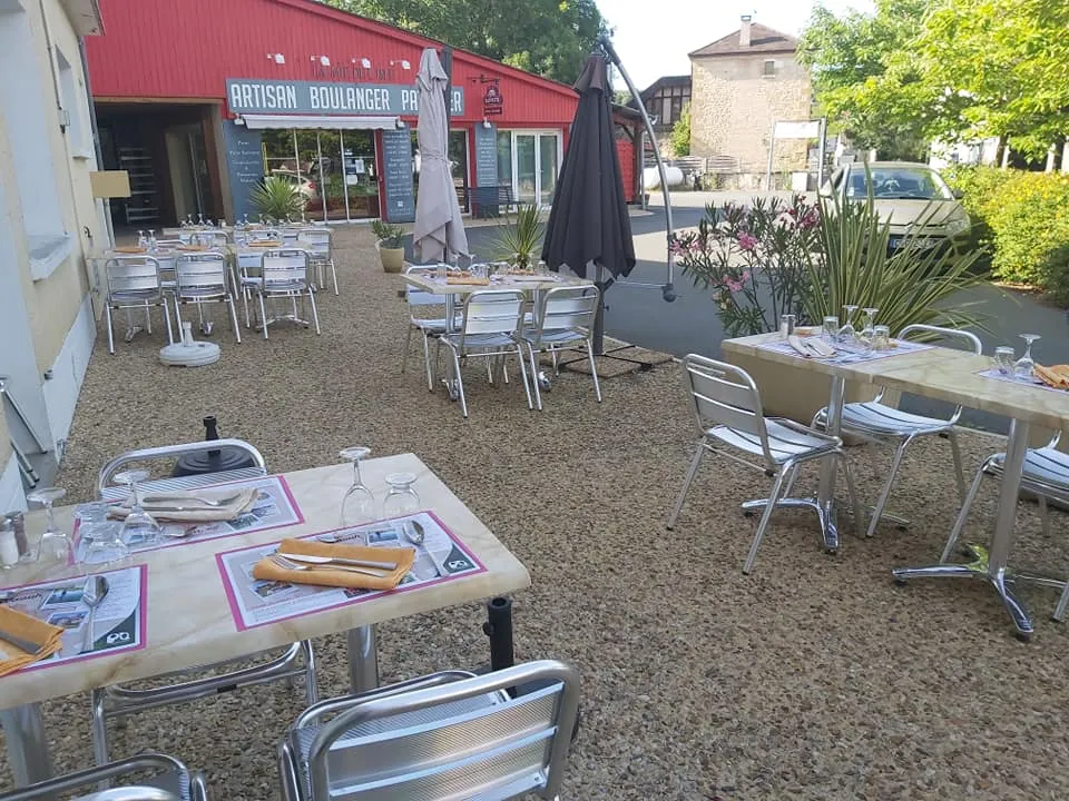 Terrasse extérieure d'un restaurant avec tables dressées, parasols et végétation